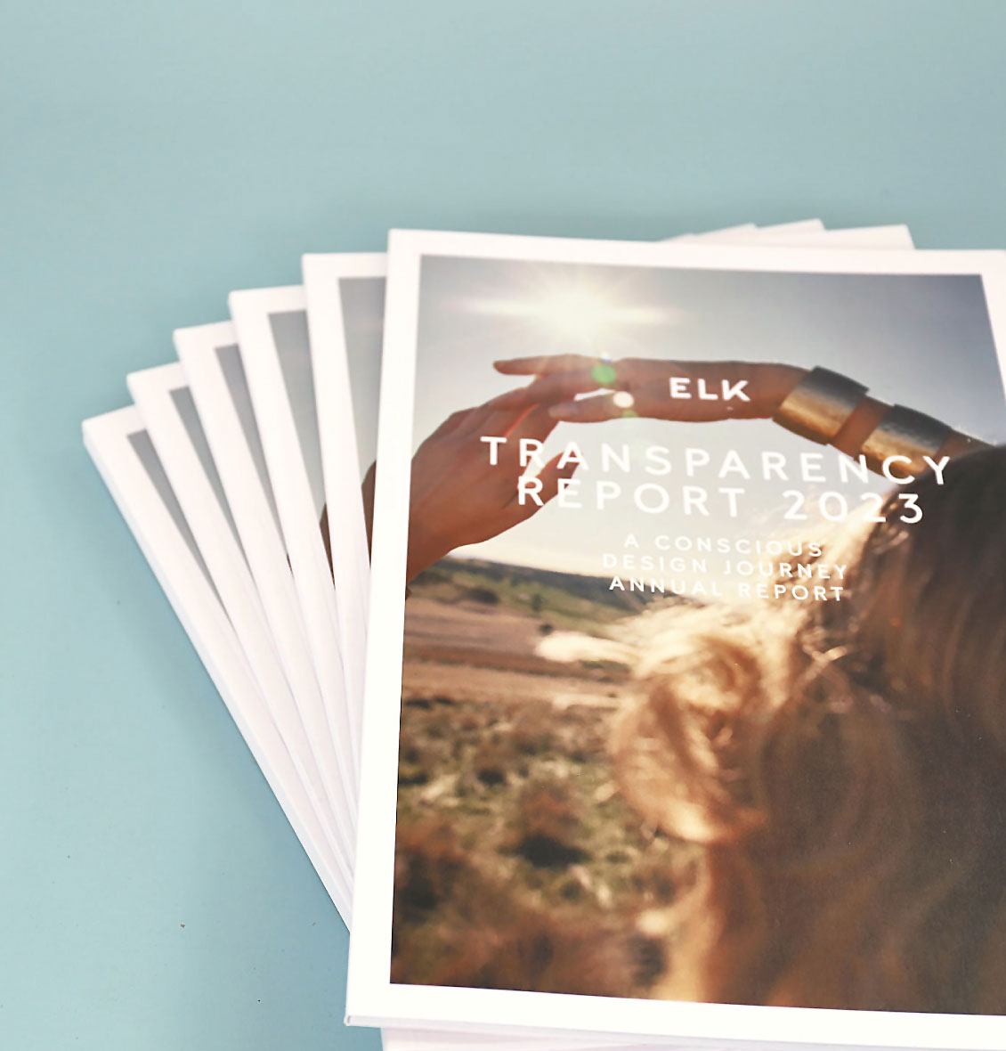 ELK Transparency Report 2023 showcasing the annual conscious design journey with multiple printed copies on a blue background