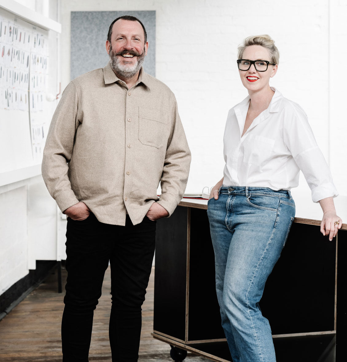 ELK co-founders and brand director pose in a bright, minimalist studio. One wears a beige shirt; the other, a white shirt with jeans