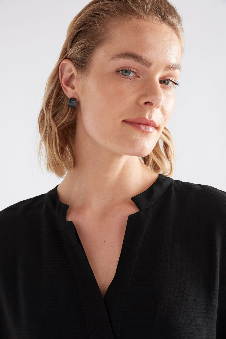 The Illsta Mini Hoop Earring features a sculptural silhouette with a glossy enamel finish, blending classic style with a bold edge, shown on model | BRIGHT NAVY