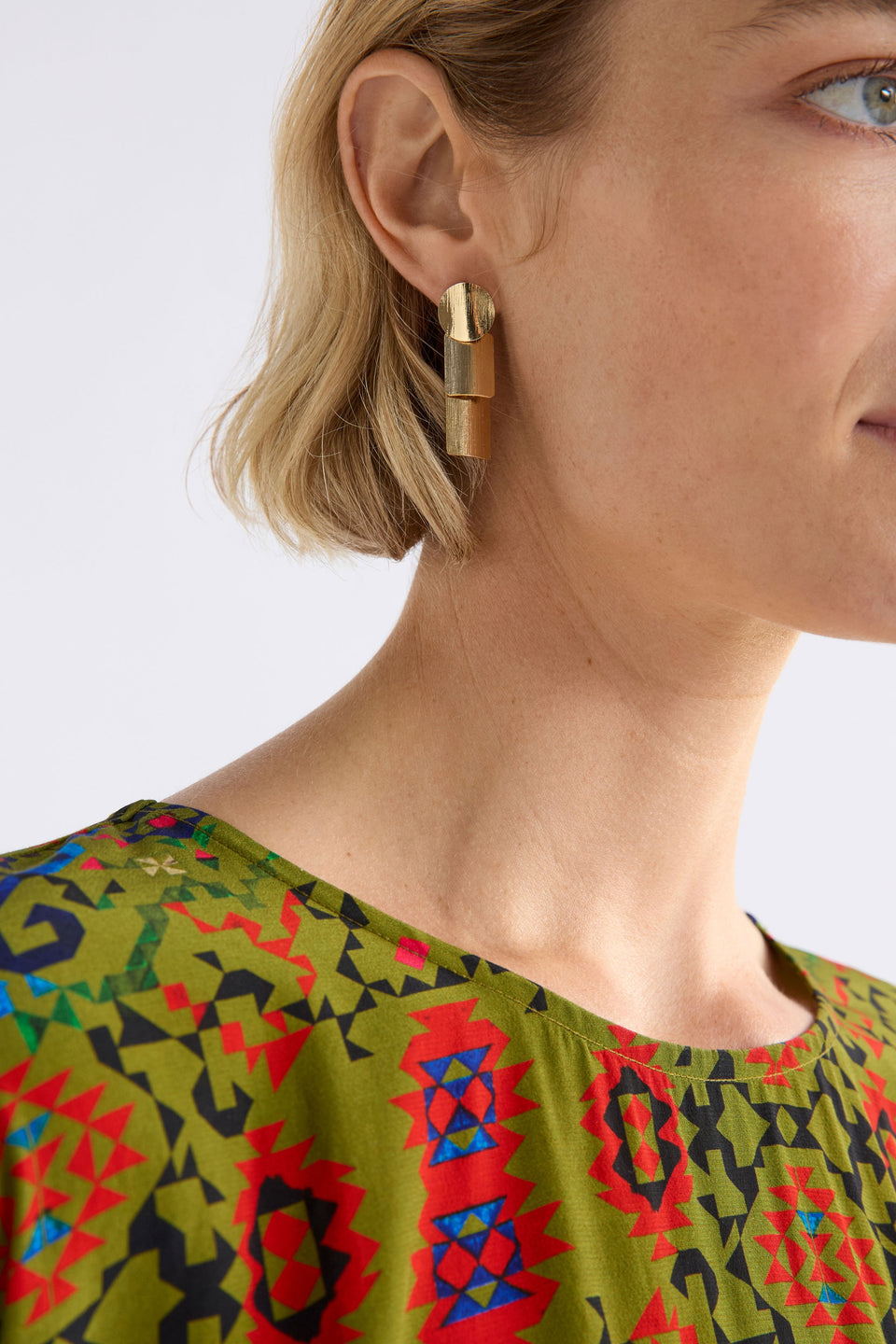 The Paerr Drop Earring features two rounded rectangles and a circle in a vertical row, creating a mid-sized sculptural drop style on model ELK | GOLD