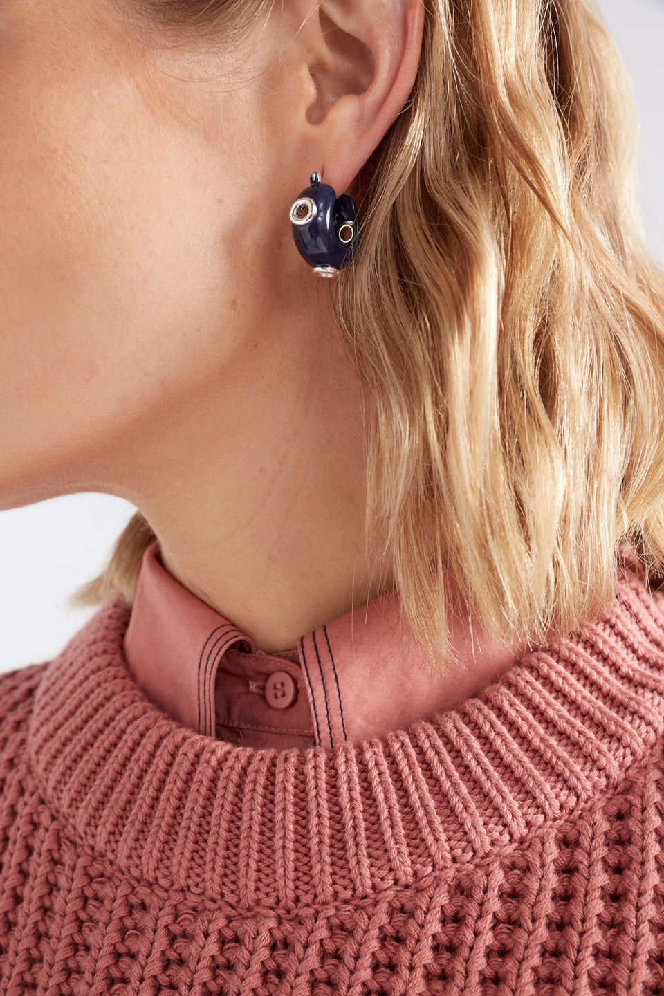 The Jans Hoop Earring features a chunky mini hoop silhouette with glossy enamel and metallic rivet detailing for a bold, playful finish, close up shown on model | BRIGHT NAVY