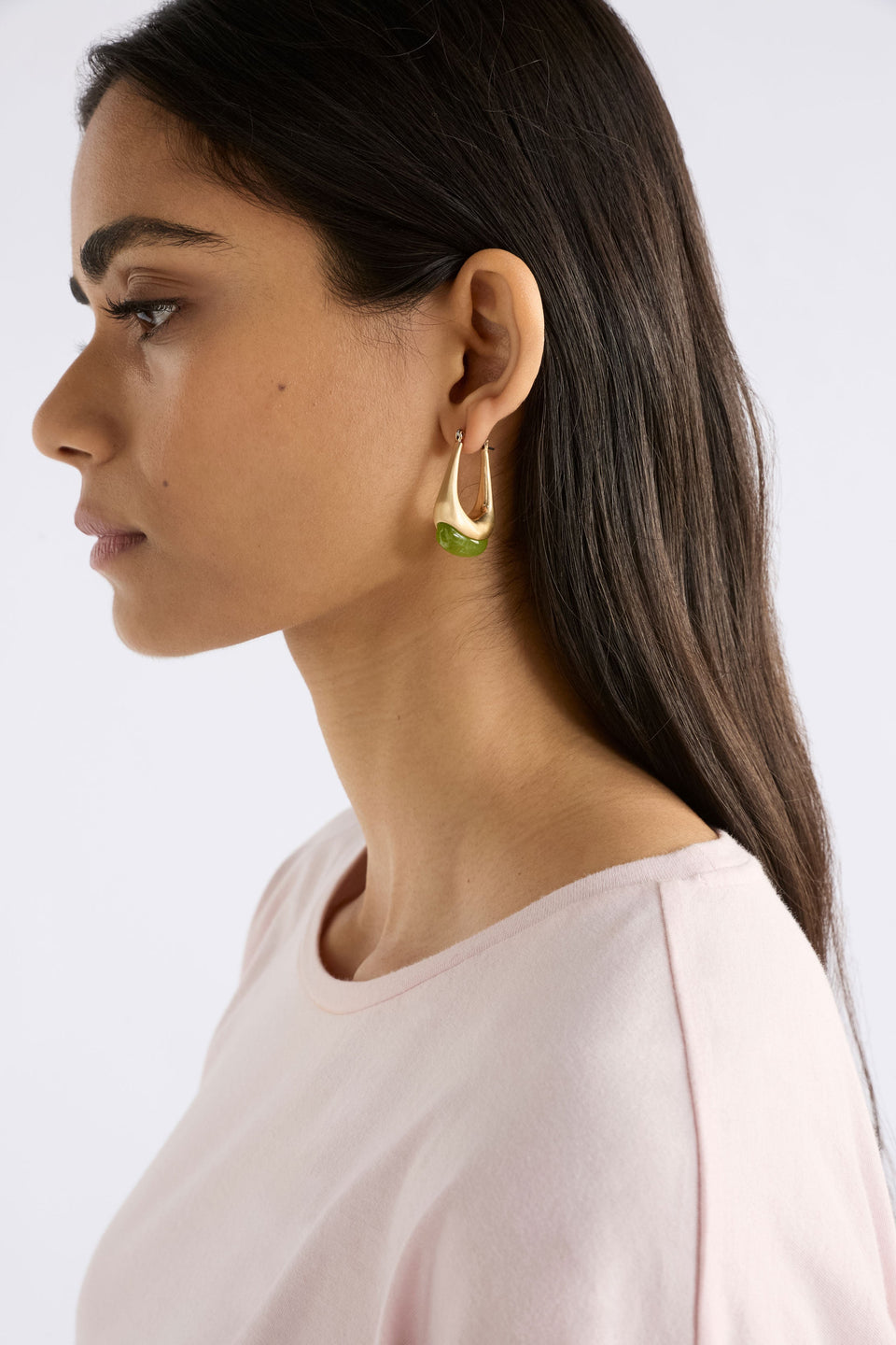 The Korvvo Long Hoop Earring features an elongated sculptural hoop with a coloured flecked glass bead, adding bold elegance to evening looks, shown on model | CELERY