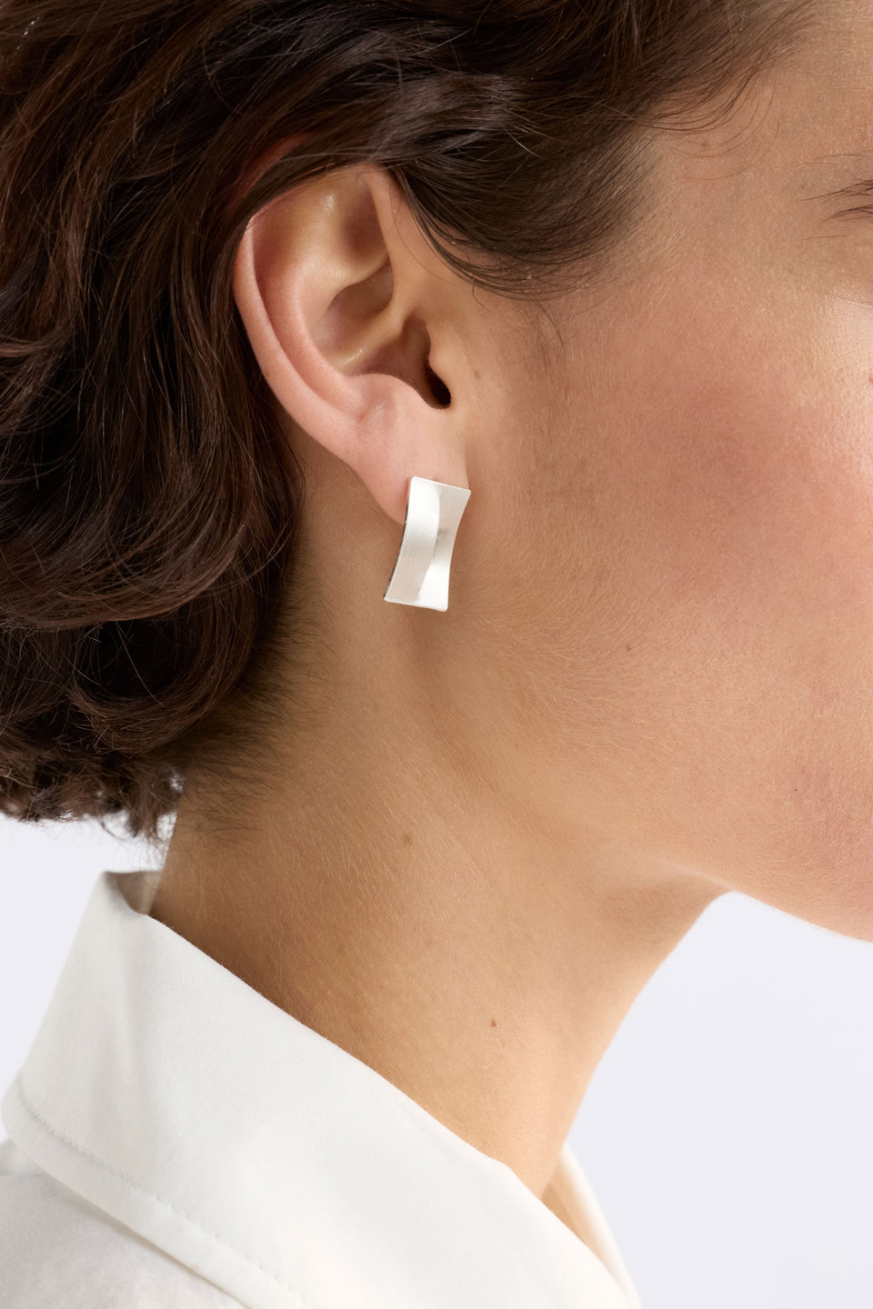 The Trel Stud Earring features a sleek rectangular shape with a folded cut-out detail, blending minimalism with sculptural edge, shown close up on model | SILVER