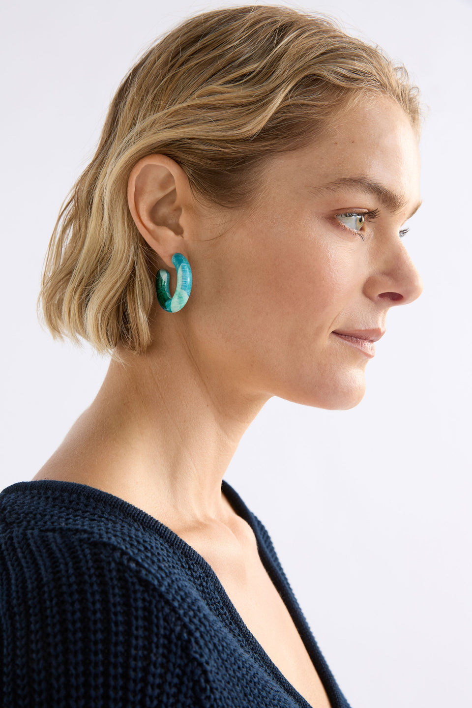 The Resso Hoop Earring features a mid-sized open resin hoop with a contemporary silhouette and playful all-over printed design, shown on model | GREEN KOMI PRINT