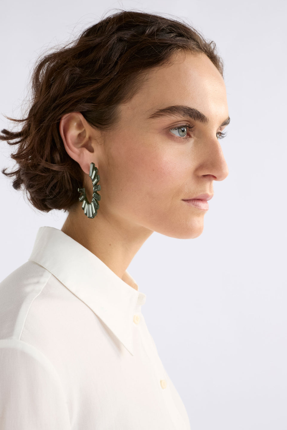 The Jule Large Hoop Earring features a circular fan of tonal glass beads radiating from a large hoop for a fun, glistening statement on model ELK | DARK OLIVE