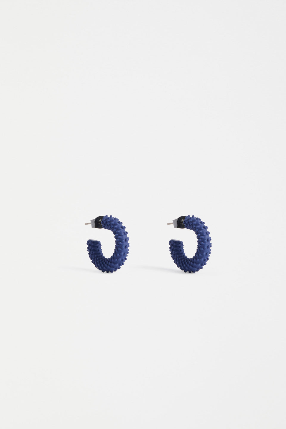 The Ekstaa Mini Hoop Earring features a textured small hoop design with a soft matte rubberised finish in bold colourways ELK | NAVY