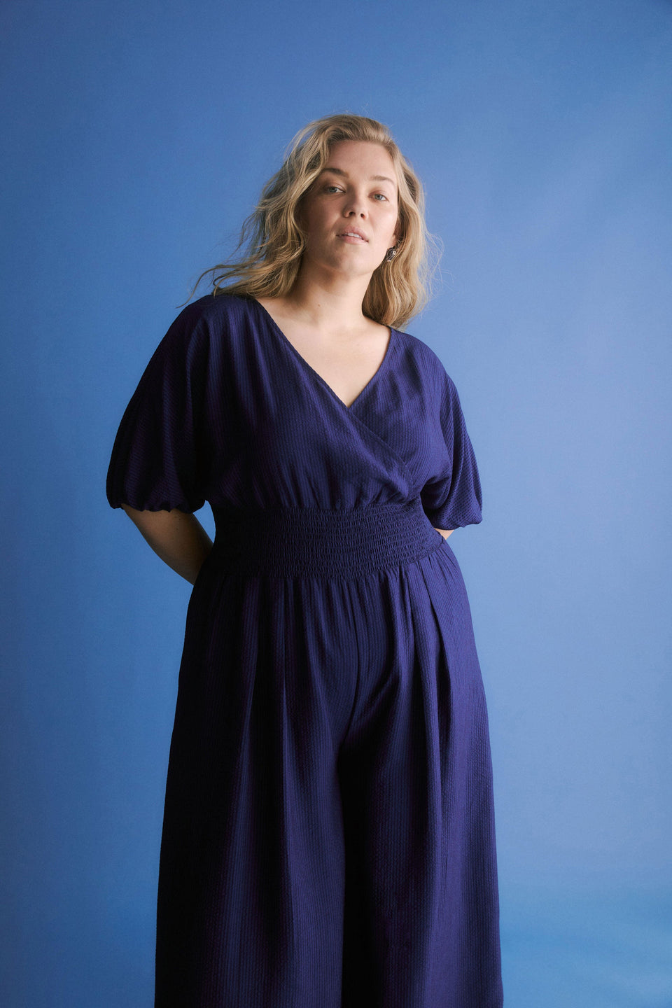 Stolt Seersucker Short Puff Sleeve Wide Leg Shirred Waist V-neck Jumpsuit ELK Curve campaign Model front crop | MID WASH