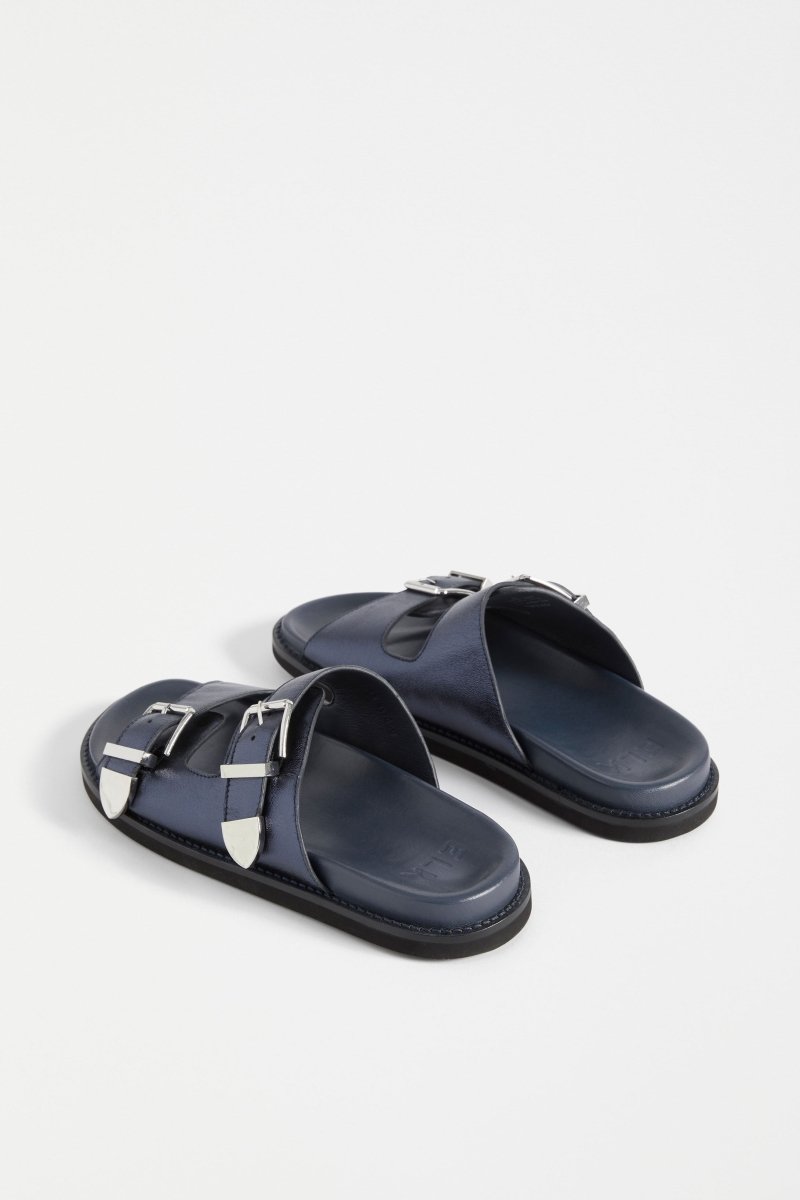 The Spenne Sandal features dual buckled foiled leather straps with tonal western hardware in a metallic slide design ELK | NAVY