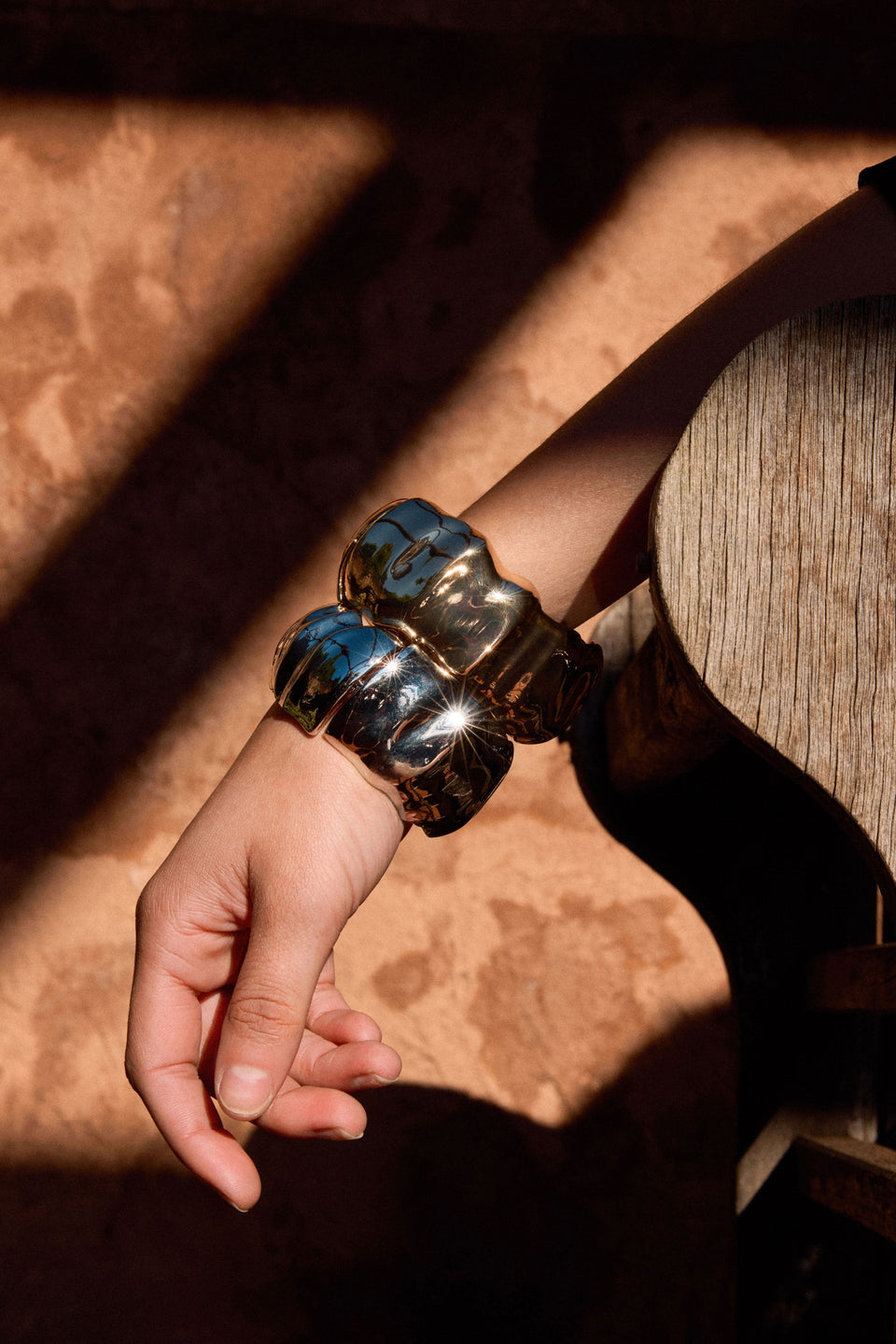 Sculptural metallic bangle with soft folds and a polished finish shown on Campaign model ELK | GOLD