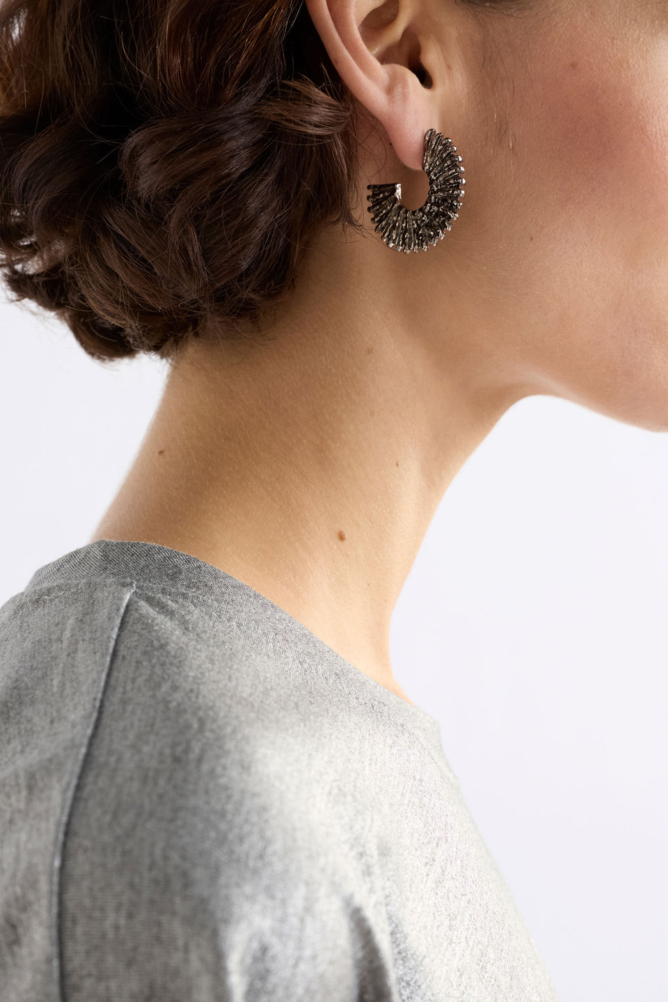 The Krusen Hoop Earring features a mid-sized open hoop crafted from shiny metal with a distinctive ridged texture ELK | GUNMETAL