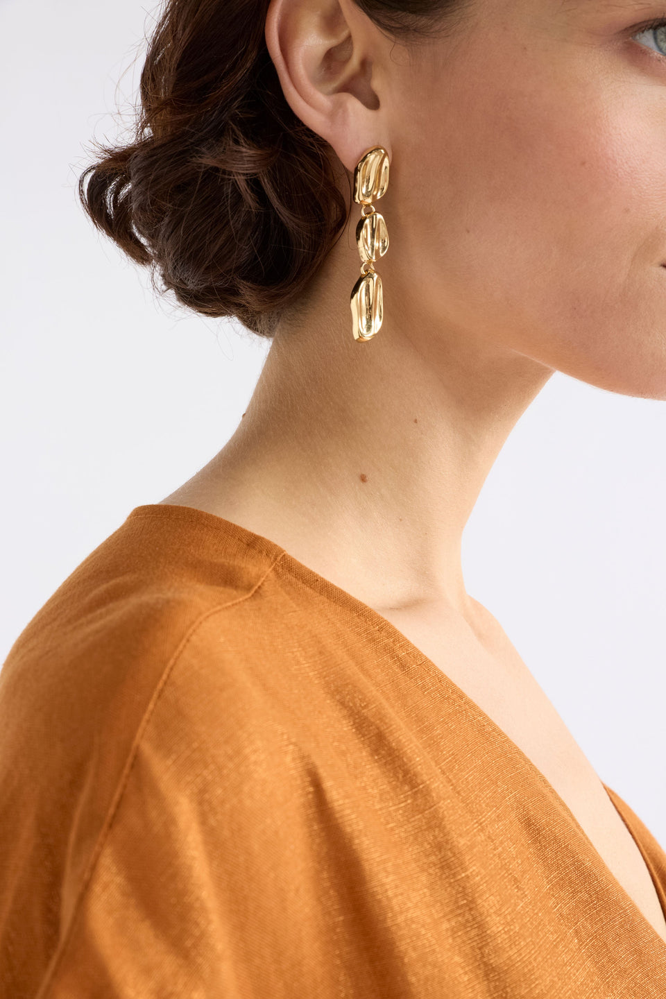The Delaa Drop Earring features three sculptural rounded shapes linked for soft, organic movement, on model  ELK | GOLD