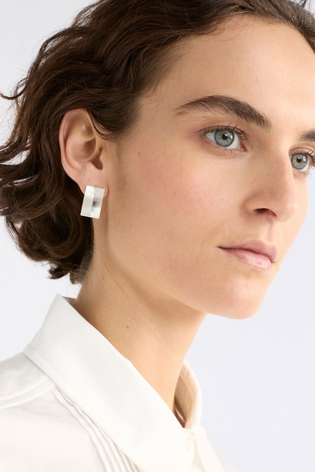 The Trel Stud Earring features a sleek rectangular shape with a folded cut-out detail, blending minimalism with sculptural edge, shown on model | SILVER