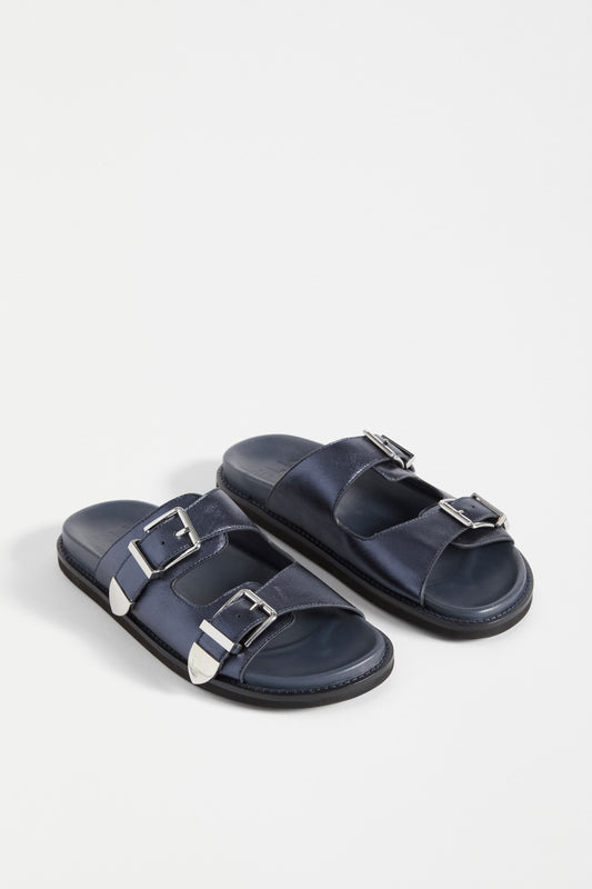 The Spenne Sandal features dual buckled foiled leather straps with tonal western hardware in a metallic slide design ELK | NAVY