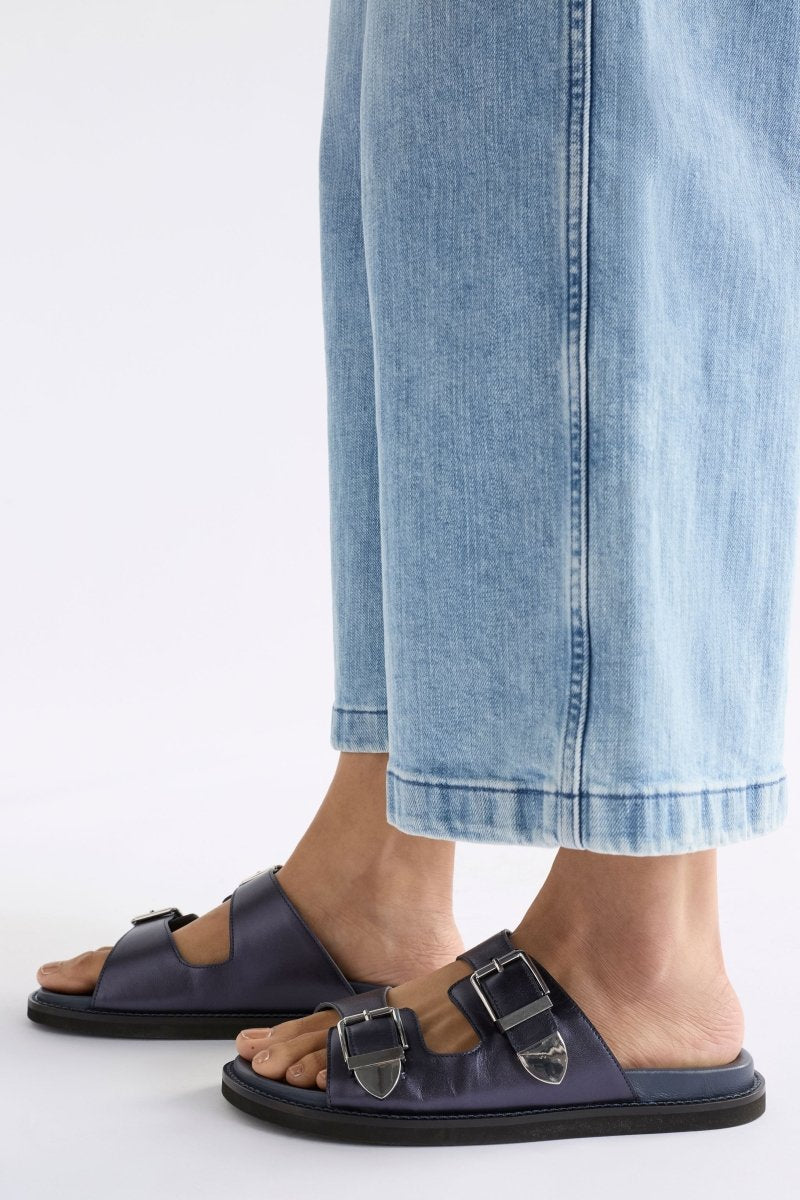 The Spenne Sandal features dual buckled foiled leather straps with tonal western hardware in a metallic slide design ELK | NAVY
